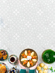 Novruz Azerbaijan traditional table setting, delicious sweet pastry on white oriental background with tea cup, teapot, green wheat grass semeni, plate of pakhlava and shekerbura and gogal, copy space
