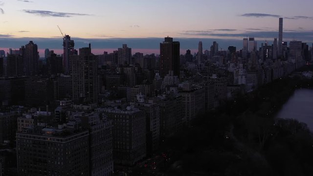 Epic drone flyover of New York City's Central Park Onassis Reservoir with great view of 5th Avenue and the Upper East Side at dawn daybreak sunrise blue hour.  in 4K.