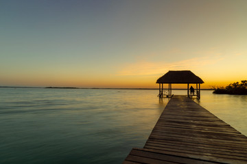 Man meditating at sunrise in the Bacalar lagoon(lagoon of the seven colors) Quintana Roo Mexico