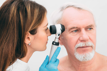 Doctor examining patient skin moles with dermoscope