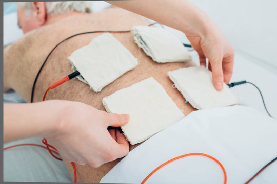 Physiotherapeutic treatment. Senior patient having ultrasound and electrotherapy treatment on his back