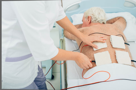 Physiotherapeutic treatment. Senior patient having ultrasound and electrotherapy treatment on his back