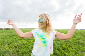 Fun, holi festival and holidays concept - Funny woman covered with color powder smiling over nature background