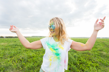 Fun, holi festival and holidays concept - Funny woman covered with color powder smiling over nature...
