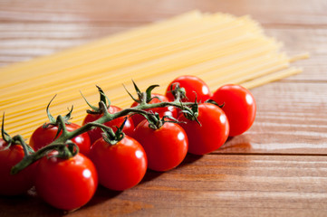 Spaghetti and cherry tomatoes on a wooden table. Homemade food or restaurant. Ingredients for cooking. National Italian healthy food.