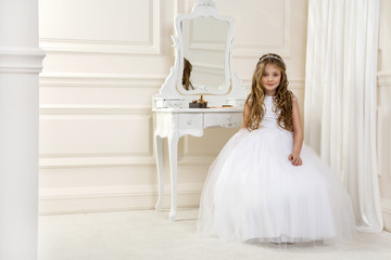 Portrait of cute little girl on white dress and wreath on first holy communion background church...