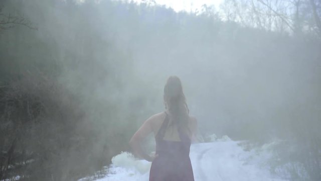Walking female model dressed in red dress in a cloudy smoke while photo shoot captured in super slow motion