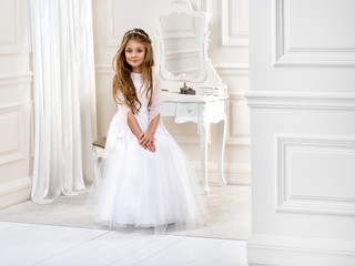 Portrait of cute little girl on white dress and wreath on first holy communion background church...