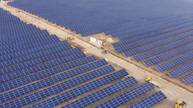 Aerial view of the giant solar power station (solar electricity plant) under construction with a lot of lineman workers