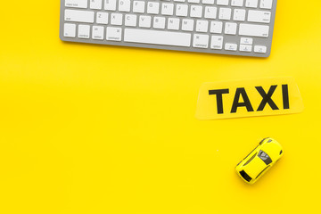 Taxi operator concept. Order taxi online. Sign ner car toy and keyboard on yellow background top view copy space