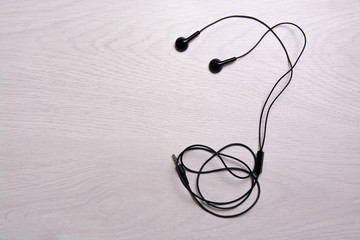 Black headphones lie on a white wooden table.