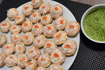 Avocado y deliciosos canapés de atún decorados con mayonesa y trozos de tomate