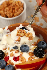 Woman eating muesli granola breakfast with yogurt