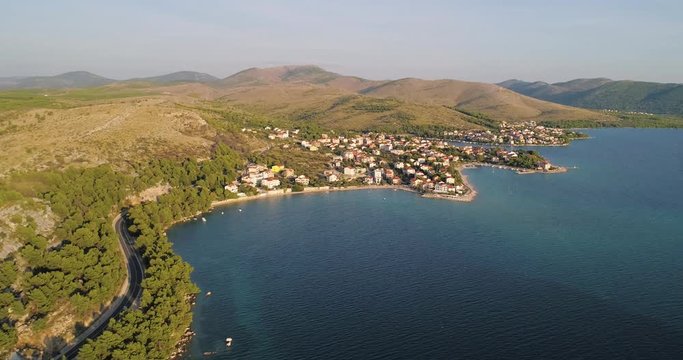 Aerial, reverse, drone shot, parallel to the mediterranean shore and above the adriatic sea, away from the Zaboric town, on a sunny, summer evening, in Croatia
