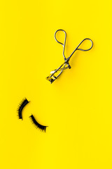 decorative cosmetic set with lash curler on yellow woman desk background top view mock up