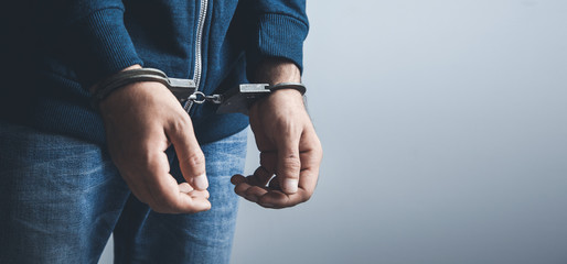 young man hand handcuffs on dark background