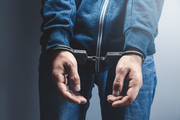 young man hand handcuffs on dark background