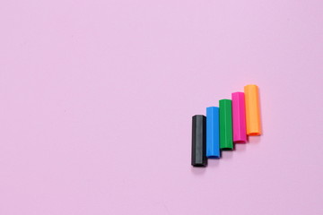 Obraz premium Five colorful pen cap on a pink millennial background. Space to insert the text. Office stuff. Minimalism. Metaphor to teamwork and hierarchy