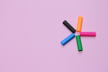 Five colorful pen cap on a pink millennial background. Space to insert the text. Office stuff. Minimalism. Metaphor to teamwork and hierarchy