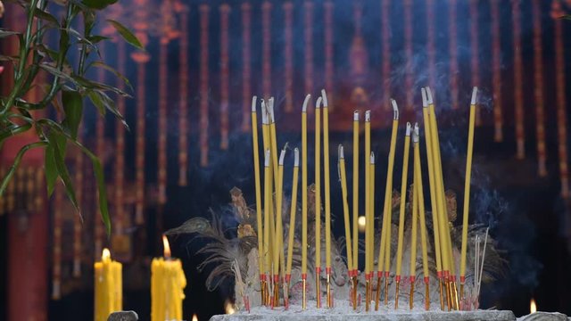 Incense sticks and candles burn in a Taoist temple Kian Un Keng Shrine (Kuan An Keng Shrine) or Guanyin Shrine in Bangkok. Close up, shallow depth of field.