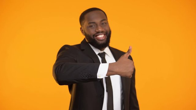 Self-confident afro-american businessman making thumbs-up gesture, good service