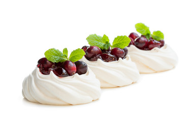 Mini Pavlova meringue nests with cranberry and mint leaves isolated on white