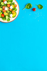 Healthy lunch. Fresh vegetable salad on blue background top view copy space