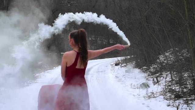 Dance move woman model dressed in red dress in a cloudy smoke while photo shoot captured in super slow motion