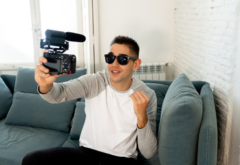 Young happy blogger recording video on camera for internet blog