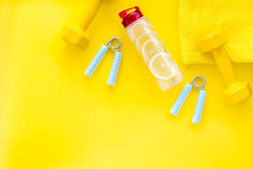 Sport with bars, towel, water and wrist builder on yellow background top view space for text