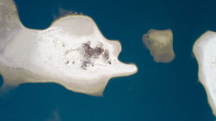 Little sand island in blue sea with lot of bold tress , areal view 