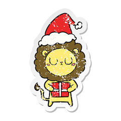 distressed sticker cartoon of a lion with christmas present wearing santa hat