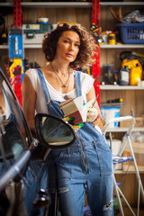 adorable woman car mechanic in blue overalls with a book-instruction