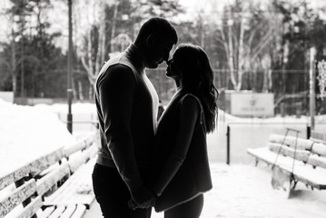 Winter love story on ice. Silhouettes of a guy and a girl. Black and white photo