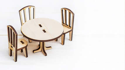 Miniature rustic wooden furniture on wooden background. Vintage table and chairs with copy space