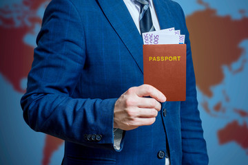 Businessman or man in a suit holds in his hand a passport with money. Traveling concept