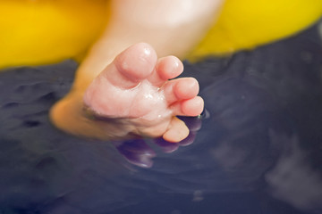Close up of caucasian child's feet underwater in bath tub. Ankle in the water. Parents wash their child's feet closeup