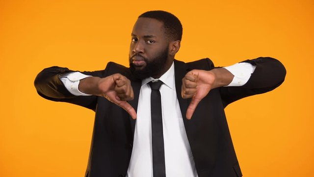 Unhappy with poor service black businessman showing thumbs-down and shaking head