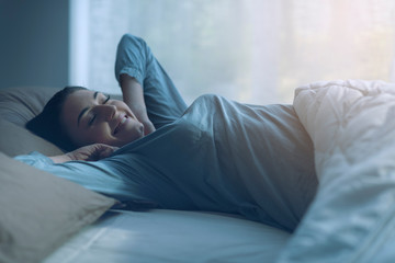 Happy relaxed woman waking up early in the morning