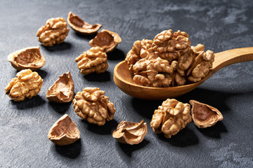 Natural walnut in wooden spoon on black table, with copy space.
