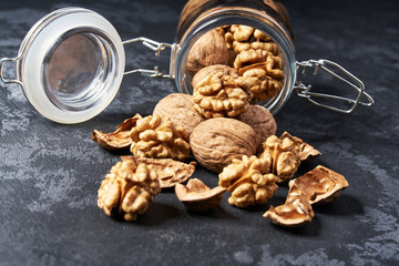Walnut in an open glass jar on black table, close-up ,