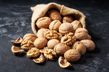Walnut are poured out of the bag on a black table, close-up.