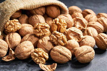 Walnut are poured out of the bag on a black table, close-up.