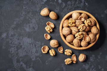 Walnut  in wooden bowl on black background with copy space. Top view