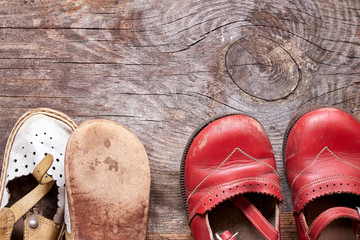 Children oldfashioned footwear on vintage wood background top view. Childhood memory