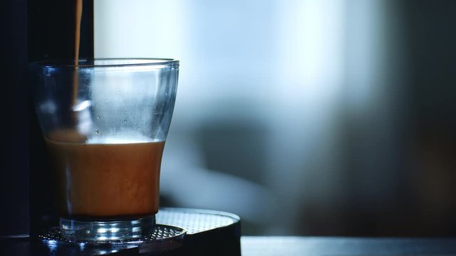 Frothy Espresso Coffee Slowly Fills a Glass with Cascading Bubbles