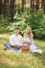 Happy young family spends time together in nature. Picnic in the forest