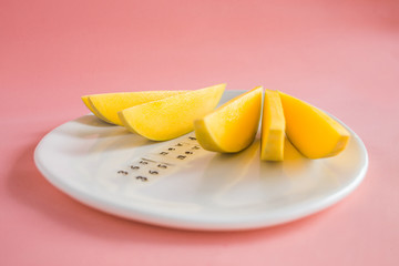 Mango fruit and mango slices on the white plate.