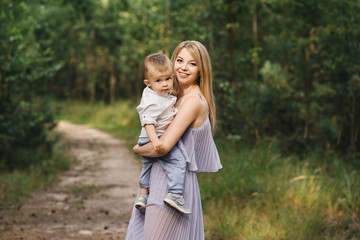 Fototapeta premium Happy young family spends time together in nature. Sweet mother with baby