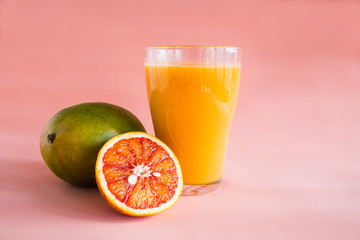 Glasses of mango, orange juice on pink background.